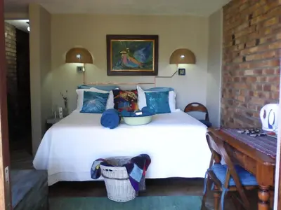 a bedroom with a large white bed and a table at KINGFISHER BLUE on Milkwood in Sabie