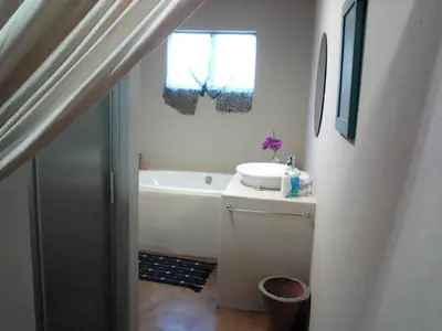 a bathroom with a tub and a sink and a window at KINGFISHER BLUE on Milkwood in Sabie