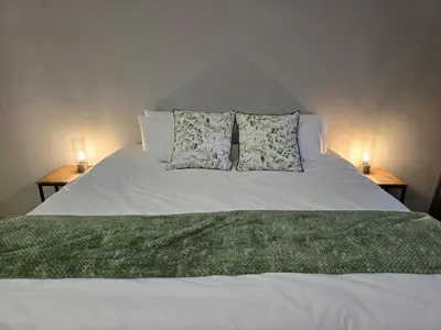 a white bed with two lamps on two tables at Meteor inn in Polokwane