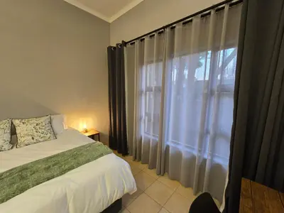 a bedroom with a bed and a window with curtains at Meteor inn in Polokwane
