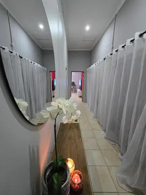 a row of white shower stalls with white curtains at Meteor inn in Polokwane