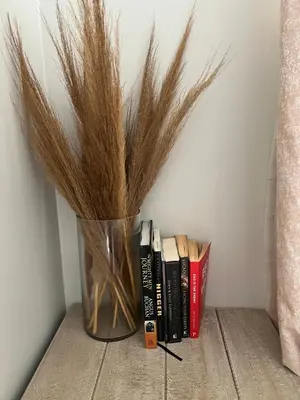 a vase filled with dry grass next to books at Nane's Tranquil Retreat in Midrand