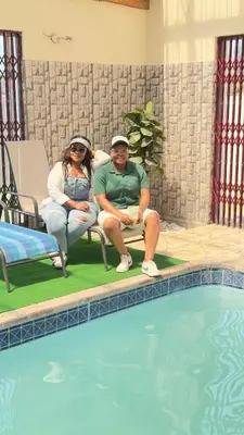 two people sitting in chairs next to a swimming pool at Hendrinas Guesthouse in Hendrina