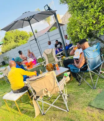 a group of people sitting in chairs under an umbrella at Hendrinas Guesthouse in Hendrina