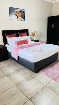 a bedroom with a large bed with pink pillows at Hendrinas Guesthouse in Hendrina