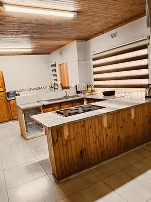a large kitchen with wooden cabinets and a counter top at Hendrinas Guesthouse in Hendrina