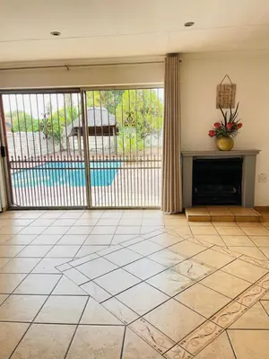 a living room with a fireplace and a pool at Chatsvilla in Boksburg