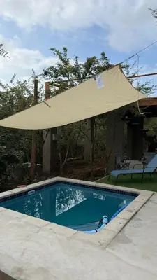 a beige umbrella over a swimming pool at Marloth Park, Self Catering Buffel st 4347 in Marloth Park