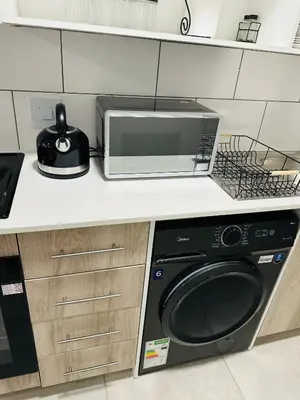 a kitchen with a microwave and a washer and dryer at Homely Stay 3 in Kempton Park