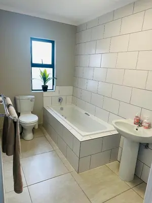 a bathroom with a tub and a toilet and a sink at Homely Stay 3 in Kempton Park