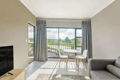 a living room with a table and chairs and a large window at Urban Waterfall Hideaway in Midrand