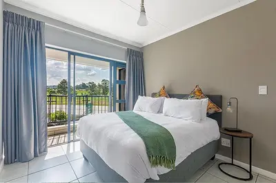 a bedroom with a large bed and a balcony at Urban Waterfall Hideaway in Midrand