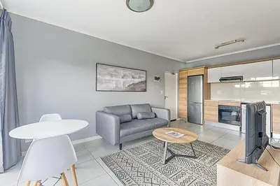 a living room with a couch and a table at Urban Waterfall Hideaway in Midrand
