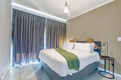 a bedroom with a large bed and a large window at Urban Waterfall Hideaway in Midrand