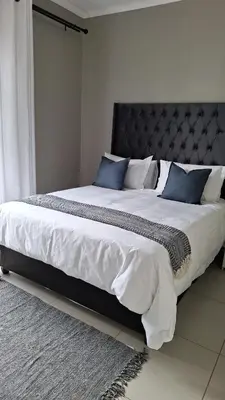 a large bed with white sheets and blue pillows at Luxury Apartments in Midrand