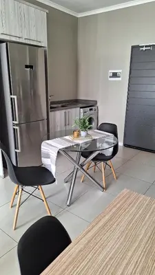 a kitchen with a table and chairs and a refrigerator at Luxury Apartments in Midrand
