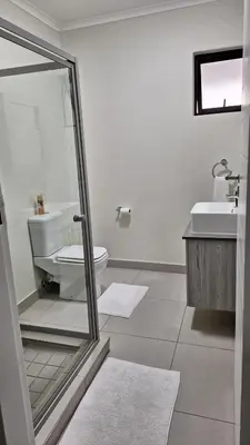 a white bathroom with a toilet and a sink at Luxury Apartments in Midrand