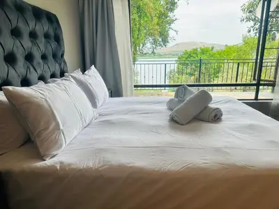 a white bed with towels on it with a window at 100 on Simon Bekker Kosmos in Hartbeespoort