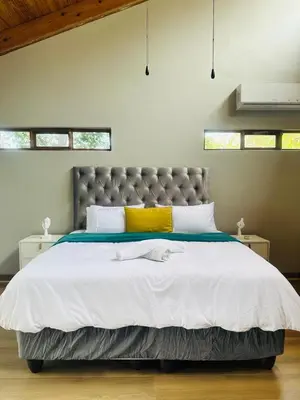 a bedroom with a large bed with white sheets and yellow pillows at 100 on Simon Bekker Kosmos in Hartbeespoort