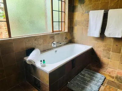 a bath tub in a bathroom with a window and towels at 100 on Simon Bekker Kosmos in Hartbeespoort