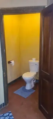 a bathroom with a toilet and a yellow wall at Stone Haven Lodge in Kliprivier