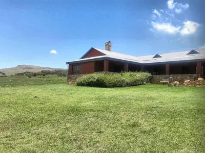 a large red house with a large grass yard at Stone Haven Lodge in Kliprivier