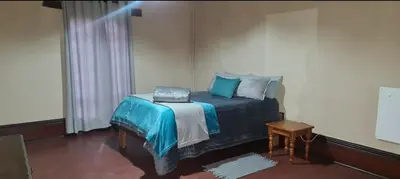 a bedroom with a bed with blue pillows on it at Stone Haven Lodge in Kliprivier
