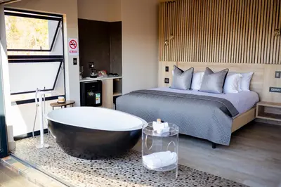 a bedroom with a large bed and a bath tub at La-Ngwenya Serenite in Warmbaths