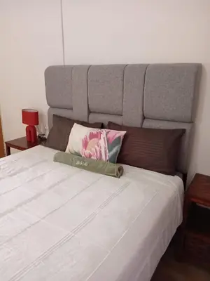 a bed with a large headboard and a pillow on it at Lu&Me in Polokwane