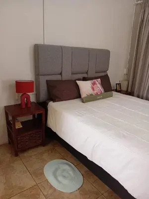 a bedroom with a large bed and a night stand at Lu&Me in Polokwane