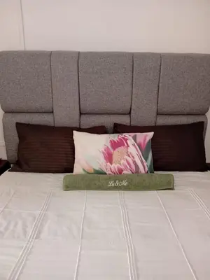 a bed with a gray headboard and pillows on it at Lu&Me in Polokwane