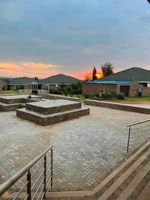 a courtyard with steps and a building with a sunset in the background at Oewerpark Landgoed Accommodation in Pretoria