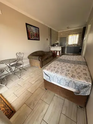 a bedroom with a bed and a couch and a table at Oewerpark Landgoed Accommodation in Pretoria