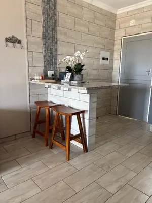 a kitchen with a counter with two stools and a refrigerator at Oewerpark Landgoed Accommodation in Pretoria