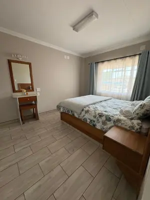 a bedroom with a bed and a table and a mirror at Oewerpark Landgoed Accommodation in Pretoria