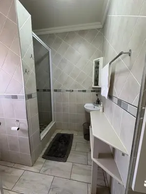 a bathroom with a shower and a sink at Oewerpark Landgoed Accommodation in Pretoria