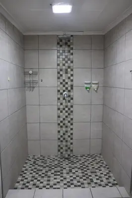 a bathroom with a shower with black and white tiles at Kudu Kottage in Phalaborwa