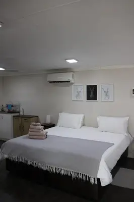 a bedroom with a large bed with white sheets and pillows at Kudu Kottage in Phalaborwa
