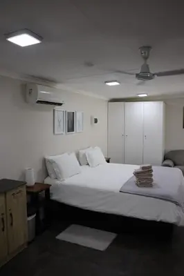 a bedroom with a large white bed and a couch at Kudu Kottage in Phalaborwa