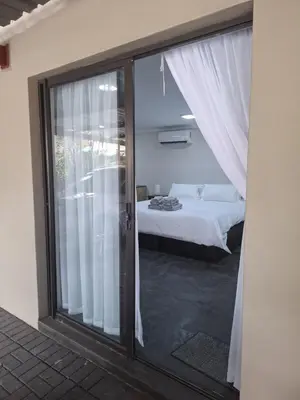 a bedroom with a bed and a sliding glass door at Kudu Kottage in Phalaborwa