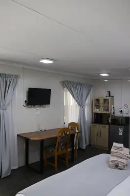 a room with a table and a tv on the wall at Kudu Kottage in Phalaborwa
