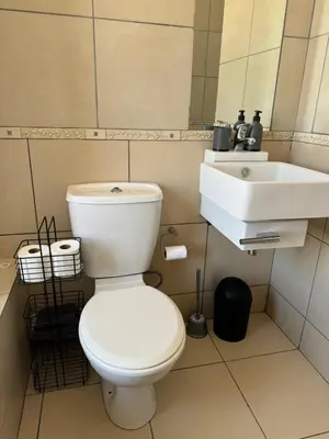 a bathroom with a white toilet and a sink at The Blue Oasis in Midrand