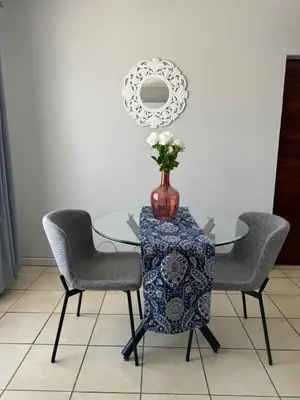 a glass table with a vase with flowers on it at The Blue Oasis in Midrand