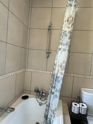 a bath tub with a shower curtain in a bathroom at The Blue Oasis in Midrand