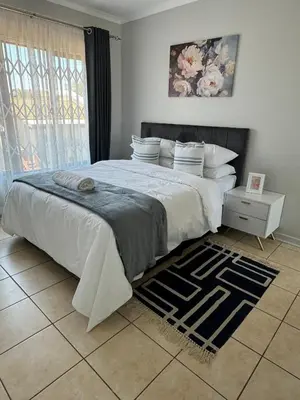 a bedroom with a large bed and a rug at The Blue Oasis in Midrand