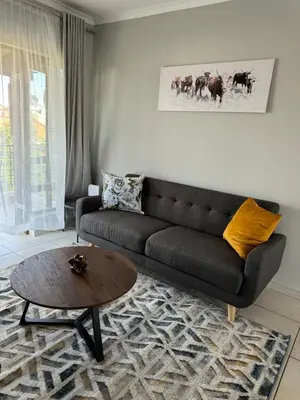 a living room with a black couch and a table at Suburban bliss in Midrand