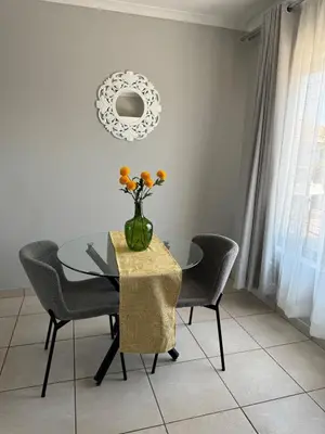 a dining room table with a vase of flowers on it at Suburban bliss in Midrand