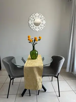 a dining room table with a vase with flowers in it at Suburban bliss in Midrand