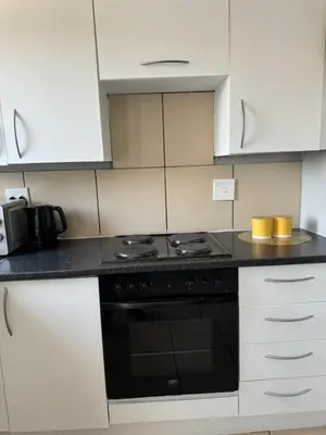 a kitchen with a black stove and white cabinets at Suburban bliss in Midrand