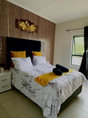 a bedroom with a bed with a yellow blanket on it at Dimension in Midrand